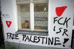 "FCK ISR" und "Free Palestine" und rote Dreiecks- Graffitti an einer Hauswand
