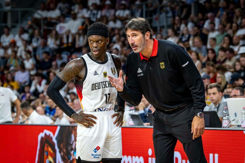 Der Trainer der deutschen Basketballnationalmannschaft erklärt einem Spieler am Spielfeldrand etwas