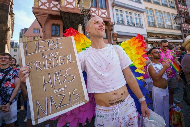 CSD-Teilnehmer Jonas Elgebete aus Bremen hält ein Plakat mit dem Schriftzug «Liebe bring Frieden - Hass bringt Nazis» auf dem Römerberg in Bremen