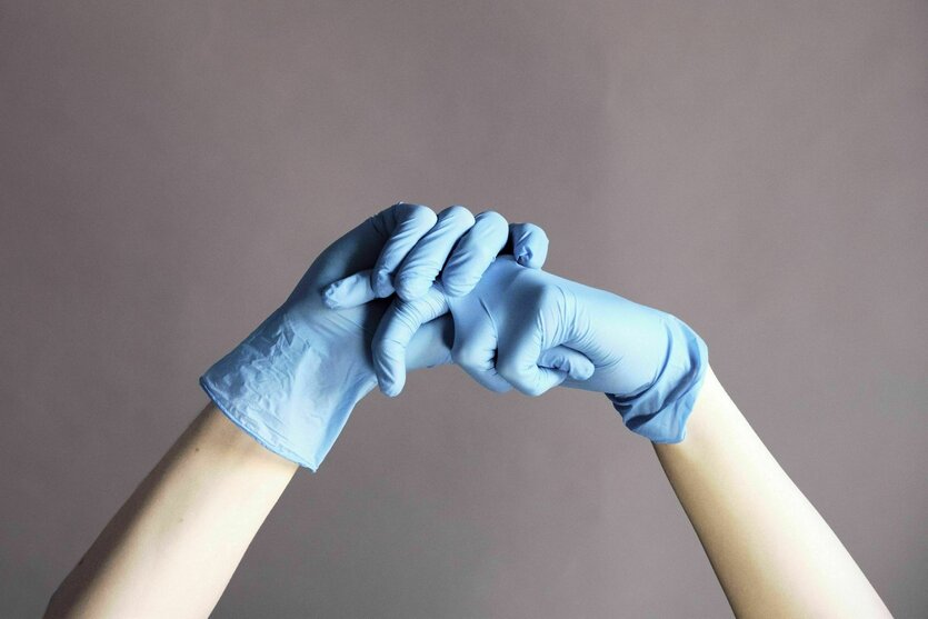 Hände mit blauen Plastikhandschuhen