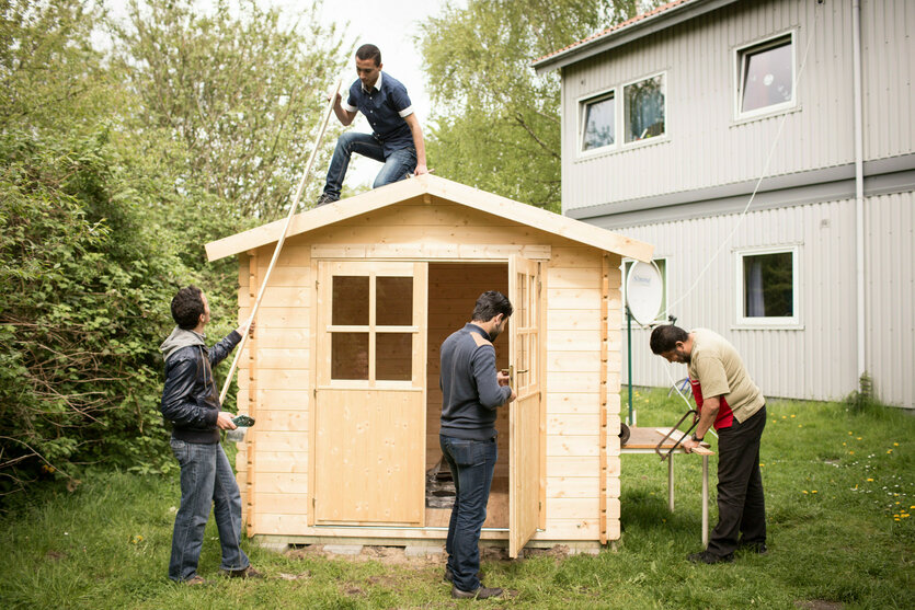 Vier Männer bauen an einem Holzhaus