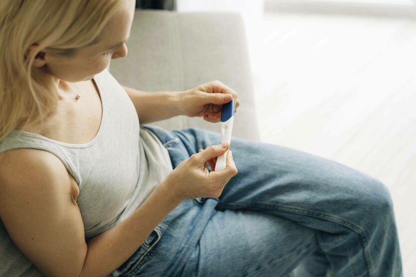 Eine Frau hält einen Schwangerschaftstest in den Händen und wartet auf das Ergebnis