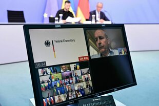 Ein Bildschirm steht vor Wolodymyr Selenskyj (hinten,l-r), Präsident der Ukraine, und dem deutschen Bundeskanzler Friedrich Merz, die an einer Videokonferenz der europäischen Staats- und Regierungschefs