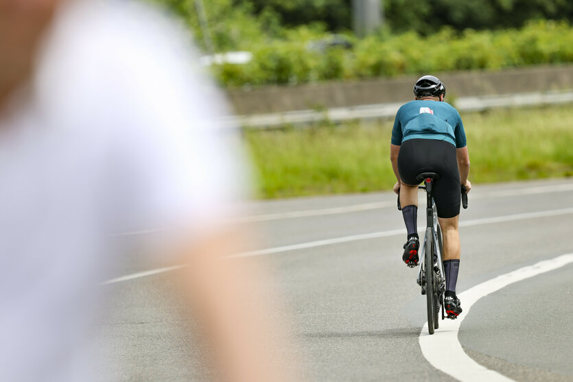 Rennradfahrer fährt auf dem Fahrbahnbegrenzungsstreifen