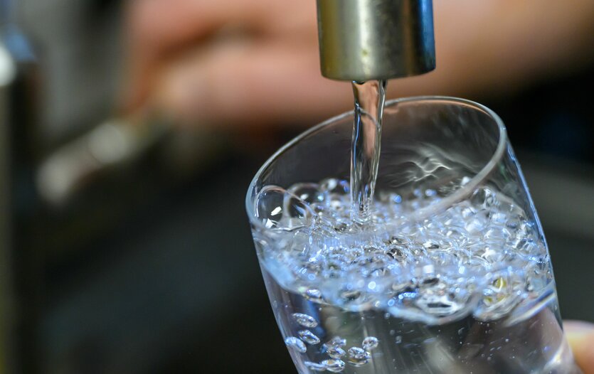 Ein Wasserglas füllt sich unter einem laufenden Wasserhahn