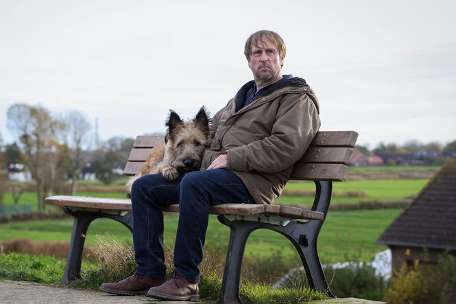 Ein Mann und ein Hund sitzen auf einer Parkbank