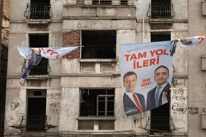 Zwei Männer sind auf einem Wahlkampf-Banner zu sehen, das an einer Hausfassade hängt