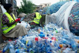 Zwei Personen inmitten von Bergen an Plastikflaschen