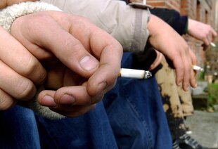 Mehrere männliche Hände, die Zigaretten zwischen den Fingern halten