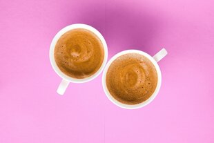 Zwei Espressotassen vor pinkfarbenem Hintergrund