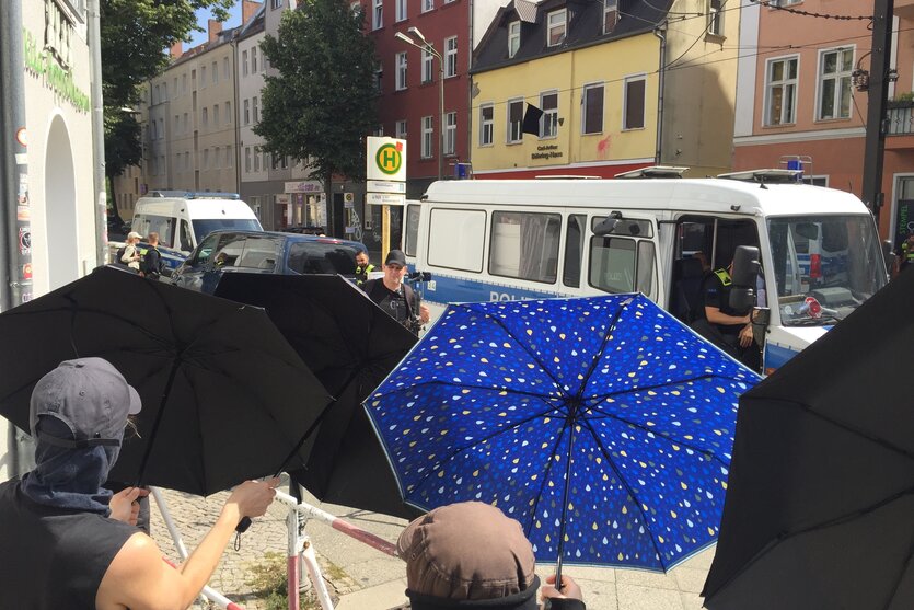 Demonstranten mit Schirmen stehen gegenber der NPD/Heimat-Parteizentrale