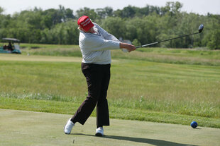 Ein älterer Mann mit einer hässlichen roten Kappe versucht sich beim Golf