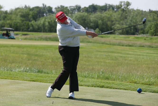 Ein älterer Mann mit einer hässlichen roten Kappe versucht sich beim Golf