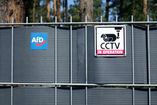 Neben dem Schild einer Überwachungskamera befindet sich ein Logo der AfD