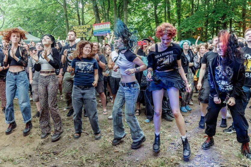 Junge Menschen tanzen auf einem Festival, Bäume im Hintergrund