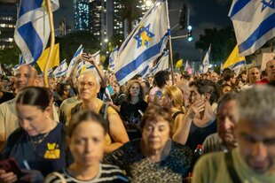 Menschen demonstrieren mit Israelfahnen, die mit einer gelben SChleife gestaltet sind