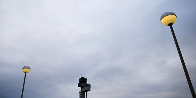 Zwischen zwei Laternen ist der Tower des Düsseldorfer Flughafens zu sehen
