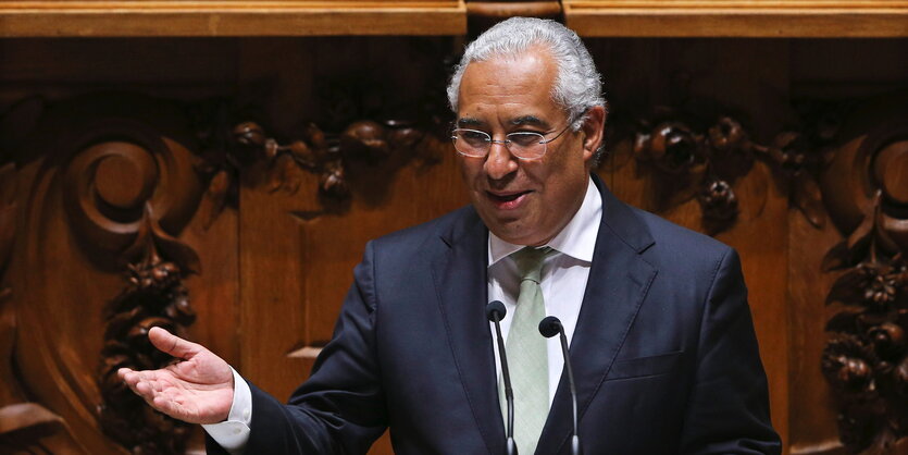 António Costa steht hinter einem Mikrophon und hebt die Hand