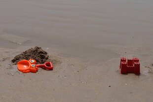 Plastikschaufel, Sandförmchen und Sandburg