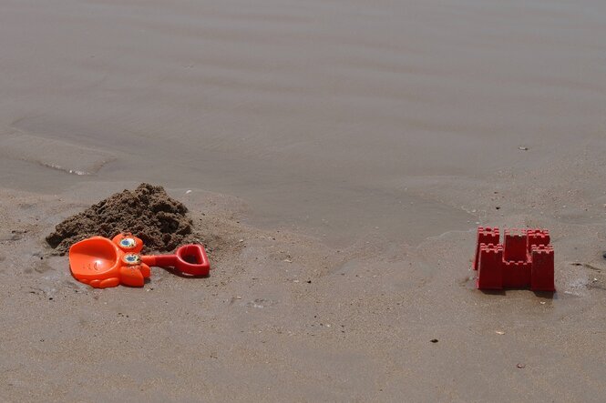 Plastikschaufel, Sandförmchen und Sandburg