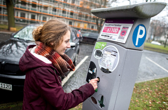 Eine Frau bezahlt am Parkscheinautomaten