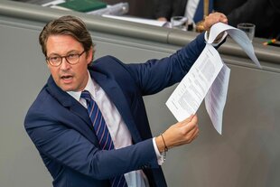 CSU-Politiker Andreas Scheuer steht im Bundestag und hält Papiere hoch