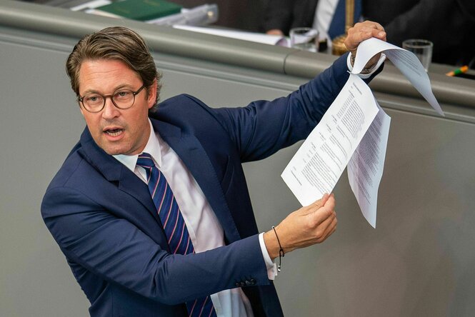 Andreas Scheuer spricht im Deutschen Bundestag und hält ein Dokument in die Höhe