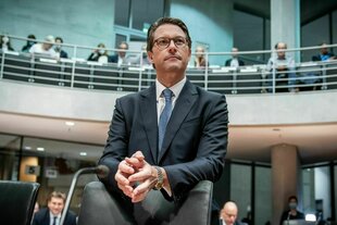 Ein Mann lehnt sich auf eine Stuhlrückenlehne