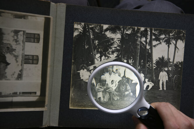 Ein Fotoalbum mit alten Fotos unter einer Lupe.