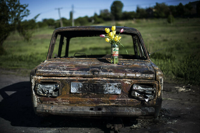 auf einem ausgebrannten Auto steht ein Blumenstrauß