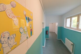 Ein blau gestrichener Flur, an den Wänden sind Kinderzeichnungen
