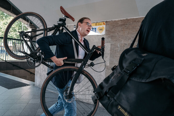 Ein Mann trägt ein Fahrrad