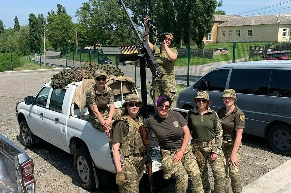 Frauen in Tarnkleidung lehnen an einem Pick-Up