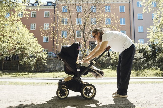 Ein Mann beugt sich zu seinem Kind im Kinderwagen