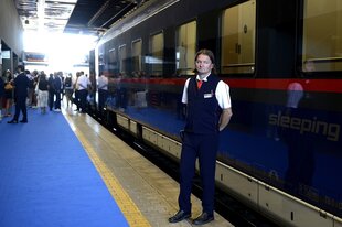 Ein Schaffner steht vor einem Nachtzug