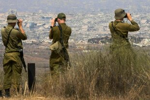 Drei Soldaten blicken durch ihre Ferngläser in den Gazastreifen