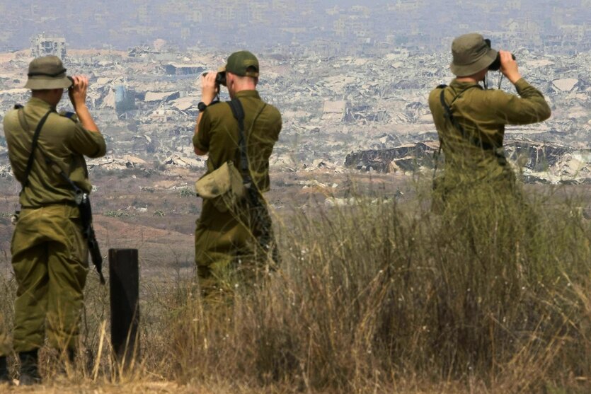 Drei Soldaten blicken durch ihre Ferngläser in den Gazastreifen