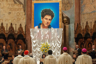 Priester vor einem Heiligenbild von Carlo Acutis