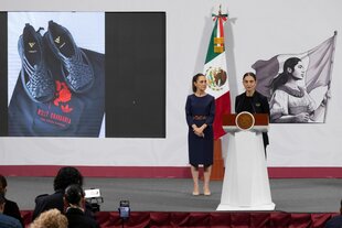 Mexikos Präsidentin Claudia Sheinbaum (l) und die Vizeministerin für kulturelle Entwicklung Mariana Núñez zeigen auf einer Pressekonferenz ein Bild von den Sandalen Oaxaca Slip-On von adidas.
