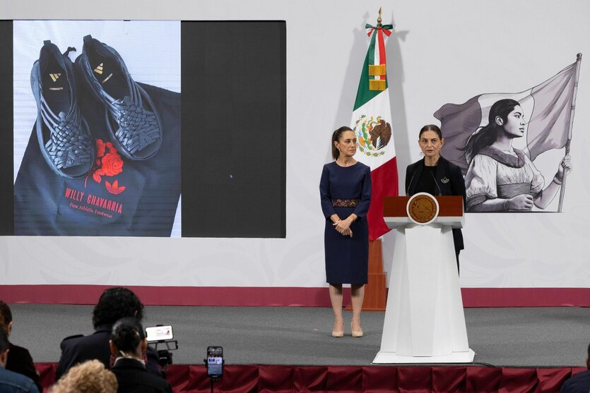 Mexikos Präsidentin Claudia Sheinbaum (l) und die Vizeministerin für kulturelle Entwicklung Mariana Núñez zeigen auf einer Pressekonferenz ein Bild von den Sandalen Oaxaca Slip-On von adidas.