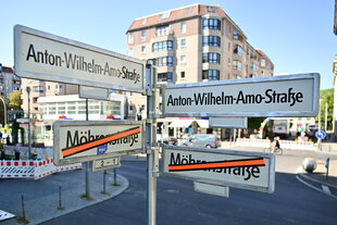 Schilder mit der Aufschrift «Anton-Wilhelm-Amo-Straße» hängen über Schildern auf denen der Name «Mohrenstraße» durchgestrichen ist