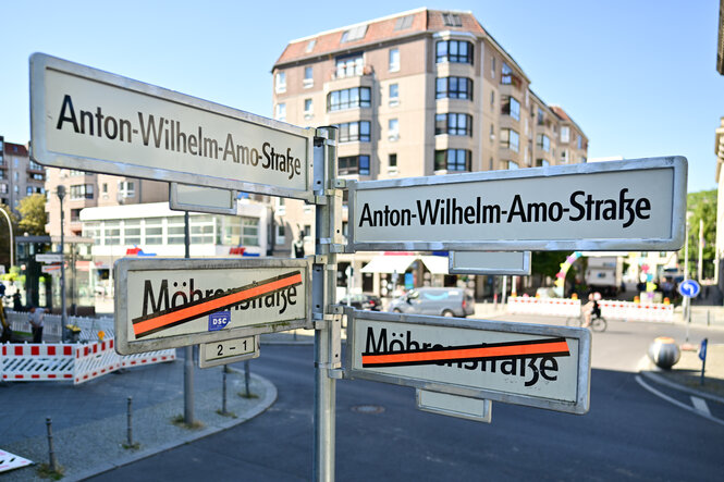 Schilder mit der Aufschrift «Anton-Wilhelm-Amo-Straße» hängen über Schildern auf denen der Name «Mohrenstraße» durchgestrichen ist