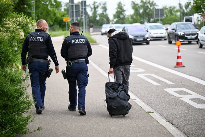 Zwei Bundespolizisten und ein Mann mit einem Koffer an einem Grenzübergang