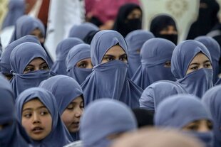 Mädchen tragen blaue Schleier und sind verhüllt