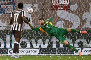 Dortmunds Torwart Gregor Kobel kann den Einschlag des Balles in sein Tor nicht verhindern, St. Paulis Oladapo Afolayan sieht unbeteiligt zu