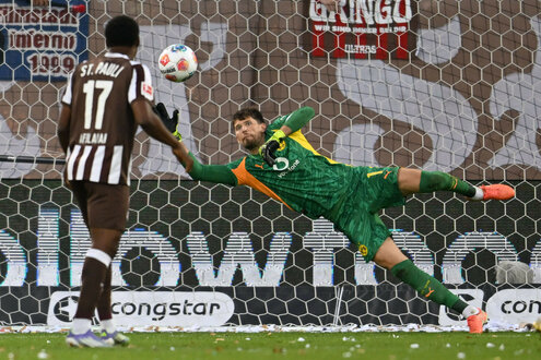 Dortmunds Torwart Gregor Kobel kann den Einschlag des Balles in sein Tor nicht verhindern, St. Paulis Oladapo Afolayan sieht unbeteiligt zu