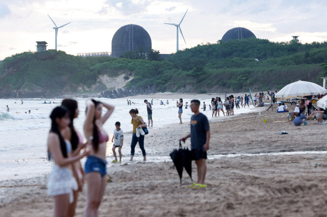 Menschen auf einem Strand, im Hintergrund das Atomkraftwerk Maanshan