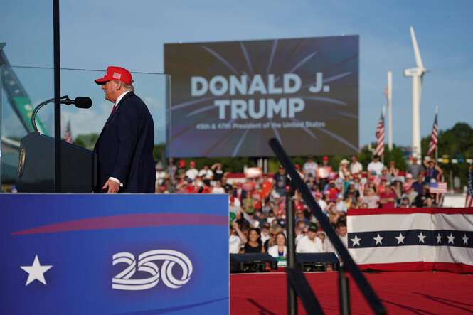 Trump spricht, im Hintergrund ein Windrad