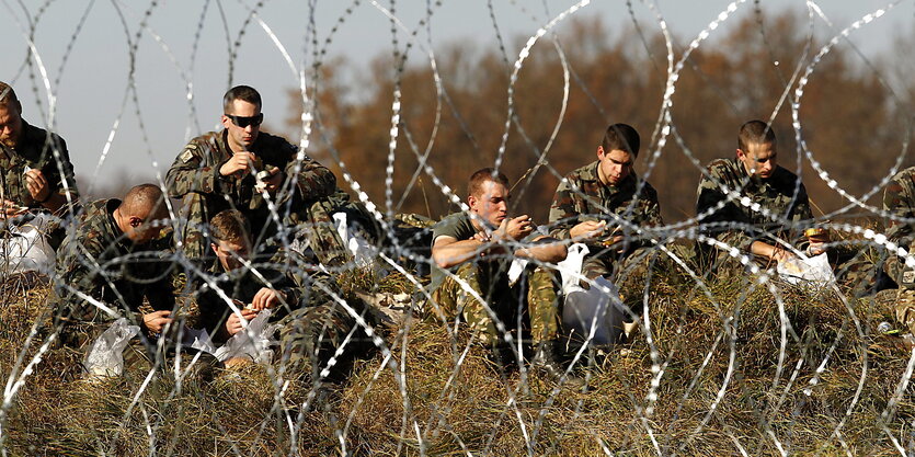 Soldaten hinter einem Stacheldrahtzaun