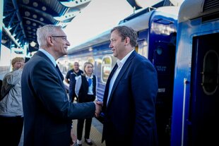Zwei Männer (Lars Klingbeil und Martin Jäger) schütteln einander an einem Bahnhof die Hände